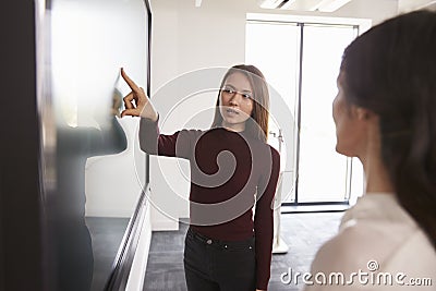 Student And Tutor Discuss Project On Interactive Whiteboard Stock Photo