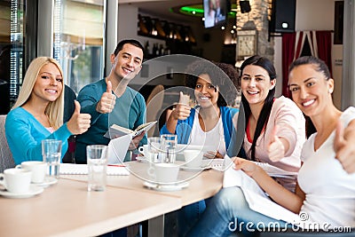 Students in cafe showing thumbs up Stock Photo