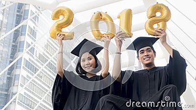 Students in graduation suit sit and gold number balloons 2018 Stock Photo