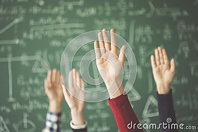 Students raised up hands green chalk board in classroom Stock Photo