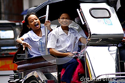 Students ride a tricycle on their way to school. Editorial Stock Photo