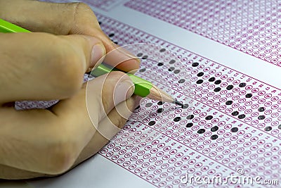 Students taking exams, writing examination room with holding pencil on optical form of standardized test with answers paper Stock Photo