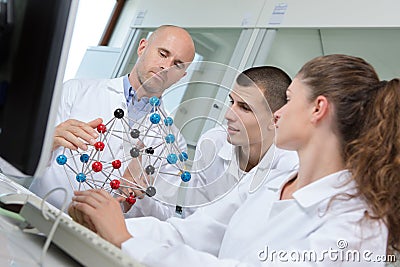 Students and teacher looking at model representing dna molecules Stock Photo