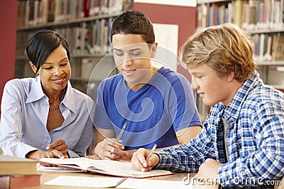 2 Students working in library with teacher Stock Photo