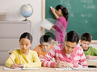 Students writing in notebook in school classroom Stock Photo