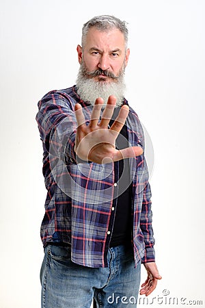 Studio portrait of bearded man in casual clothes shows hand stop sign, gesture no more, white background, copy space Stock Photo