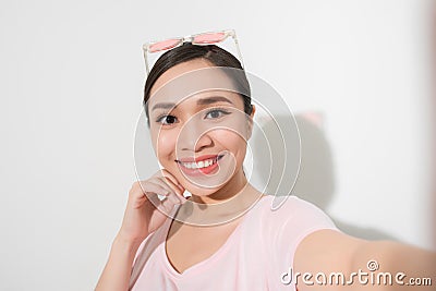 Studio portrait of beautiful woman smiling with white teeth and making selfie, photographing herself over white background Stock Photo