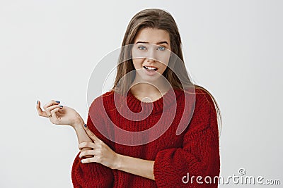 Studio portrait of doubtful unimpressed cute girlfriend in trendy loose sweater, gesturing with head and lifting one Stock Photo