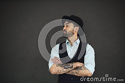 Studio portrait of handsome ethnic male with crossed tattooed arms, dressed in a blue shir Stock Photo