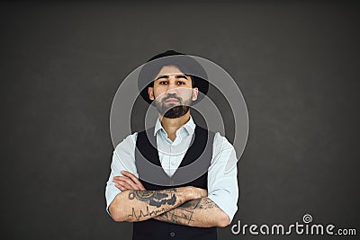 Studio portrait of handsome ethnic male with crossed tattooed arms, dressed in a blue shirt Stock Photo