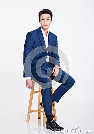 Studio portrait of a young Asian business man sitting in a chair Stock Photo