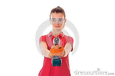 Studio portrait of young beautiful brunette girl in uniform and glasses makes renavation with drill in hands isolated on Stock Photo