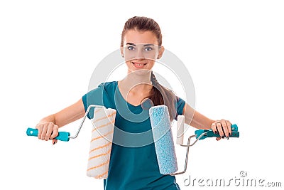 Studio portrait of young cheerful brunette girl in uniform makes renavation with paint roller in hands smiling on camera Stock Photo