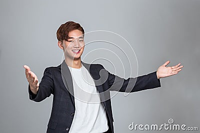 Studio portrait of a young East Asian man welcoming everyone Stock Photo