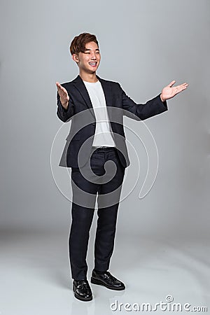 Studio portrait of a young East Asian man welcoming everyone Stock Photo