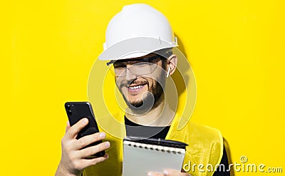 Studio portrait of young smiling man architect, builder engineer, wearing white construction safety helmet, glasses and jacket. Stock Photo