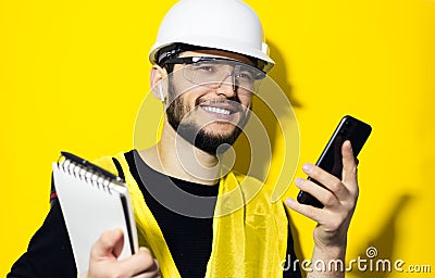 Studio portrait of young smiling man architect, builder engineer, wearing white construction safety helmet, glasses and jacket. Stock Photo