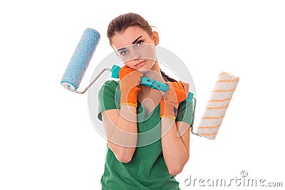 Studio portrait of young tired brunette girl in uniform makes renavation with paint roller in hands isolated on white Stock Photo