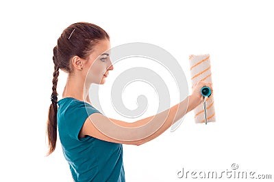 Studio profile portrait of young beautiful brunette girl in uniform makes renavation with paint roller in hands isolated Stock Photo
