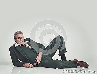 Studio, retro and mature model, fashion and lying on the floor with glasses and vintage style. Unique, portrait and man Stock Photo