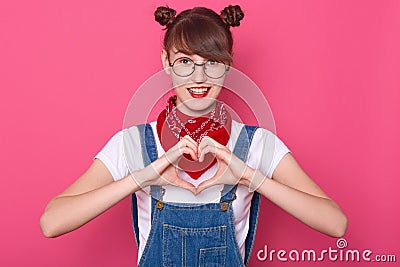 Studio shot of adorable smiling young brunette woman girl posing over pink background. People lifestyle, body language Stock Photo