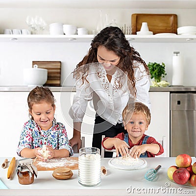 Studio shot of a family in the kitchen at home. Small children, a girl and a boy, learn to make dough rolls with their mother or Stock Photo