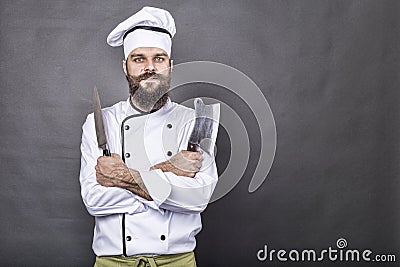 Studio shot of a happy bearded young chef holding sharp knives Stock Photo