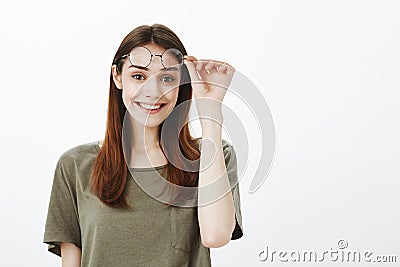 Studio shot of joyful beautiful urban female student taking off trendy round glasses and holding eyewear on forehead Stock Photo