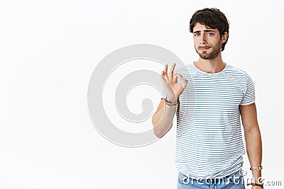 Studio shot of pressured and tired unsure young european male coworker showing okay gesture while pursing lips feeling Stock Photo