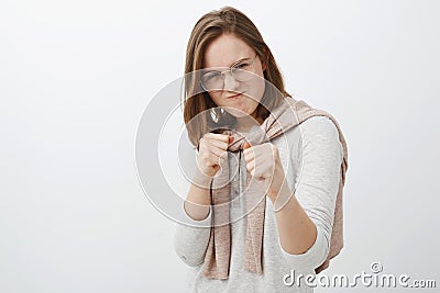 Studio shot of rebellious daring and playful female friend in glasses and sweatshirt tied over neck raising clenching Stock Photo