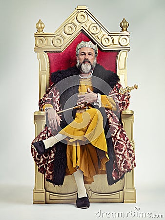 I took the throne peacefully. Studio shot of a richly garbed king sitting on a throne. Stock Photo