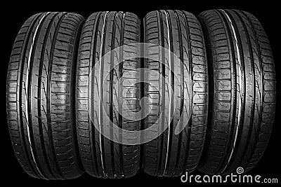 Studio shot of a set of summer car tires isolated on black background. Tire stack background. Car tyre protector close up. Black r Stock Photo