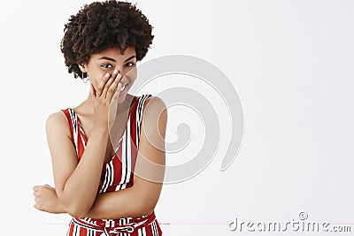 Studio shot of smart and flirty attractive feminine african american in striped overalls chuckling sensual covering Stock Photo