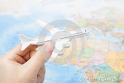 Studio shot of toy plane in hand with world map on background - focus on the plane Stock Photo