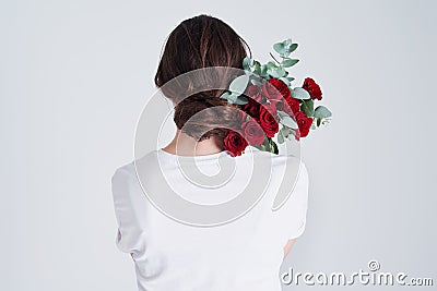 Be like a rose, strong and gentle. Studio shot of an unrecognizable woman holding flowers against a grey background. Stock Photo
