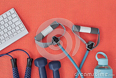 Hustle for that muscle. Studio shot of a variety of workout equipment and a keyboard on a red yoga mat. Stock Photo