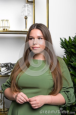 Studio shot of voluptuous woman posing in green dress over white background Stock Photo