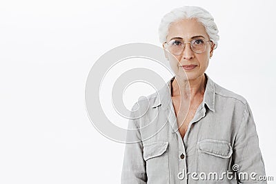 Studio shot of wise and intelligent skillful senior female doctotr in glasses with gray hair standing calm and confident Stock Photo