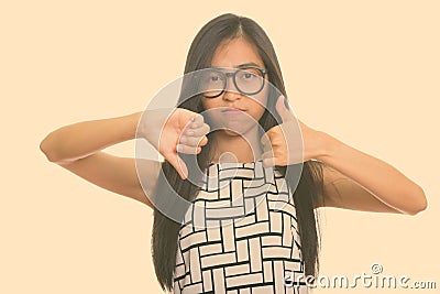 Young Asian teenage nerd girl giving thumbs up and down Stock Photo