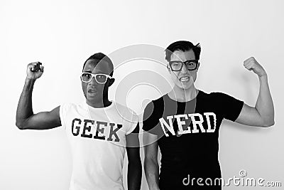 Studio shot of young black African Geek man with European Nerd man flexing arms and showing bicep muscles Stock Photo