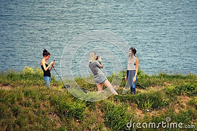 Studland, Dorset, UK - June 04 2018: Three young women taking cellphone photos of each other on a coastal headland Editorial Stock Photo