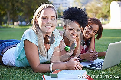 Study friends. Portrait of a group of smiling university students lying on the grass studying. Stock Photo