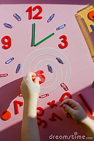 study the topic of hours with children. The watch is made of numbers, paper clips, and sticks from a children learning Stock Photo