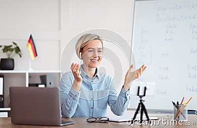 Studying German online. Cheerful Caucasian female teacher giving foreign language lesson on web using laptop Stock Photo