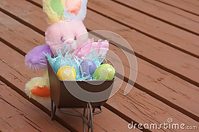 Stuffed Easter bunny with wheel barrel of eggs. Stock Photo