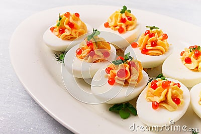 Stuffed eggs, with red caviar, micro greenery, Snack, on a white plate, top view, close-up, no people, Stock Photo