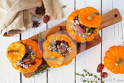 Stuffed fall mini pumpkins with rice, cranberries, cabbage and nuts over white wood Stock Photo