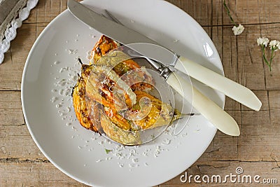 Stuffed with ricotta and cheese baked zucchini and pumpkin flowers served with a glass of mineral water. Rutik style. Stock Photo