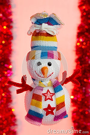 Stuffed snowman with a multicolored scarf and hat, with two buttons in the shape of a star and arms in the shape of a red branch Stock Photo