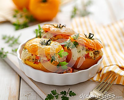 Stuffed tomatoes, baked yellow tomatoes stuffed with bulgur, vegetables and cheese with the addition of aromatic herbs in a baking Stock Photo